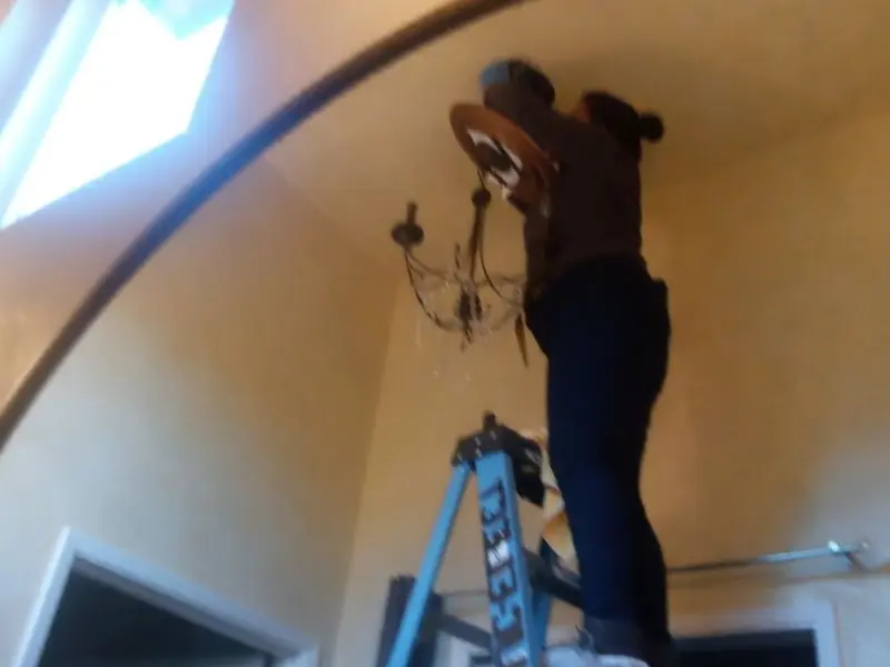Electrician installing a chandelier in a East Rancho Dominguez residence